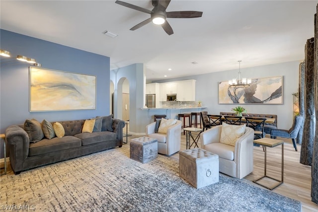 living room featuring light hardwood / wood-style flooring and ceiling fan with notable chandelier