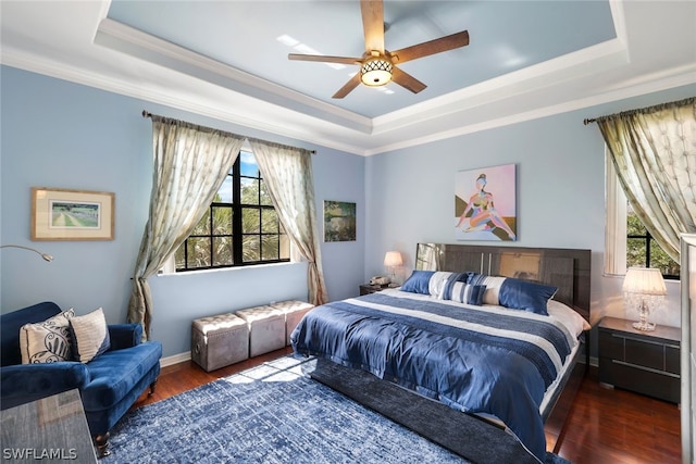 bedroom with hardwood / wood-style flooring, a raised ceiling, and multiple windows