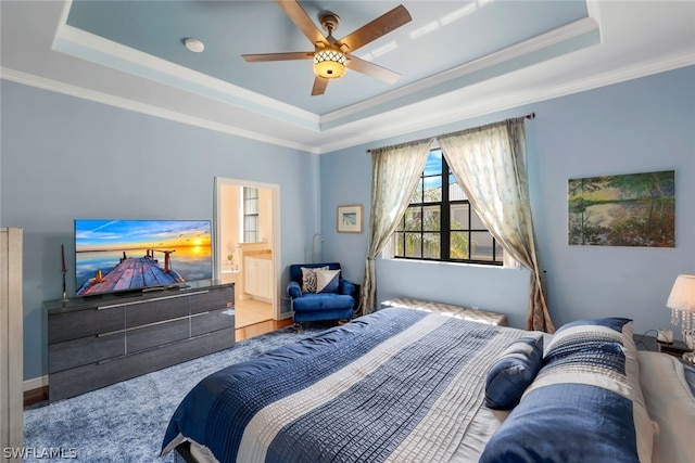 bedroom with ceiling fan, a tray ceiling, connected bathroom, and ornamental molding