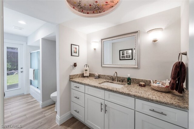 bathroom with toilet, vanity, and hardwood / wood-style floors