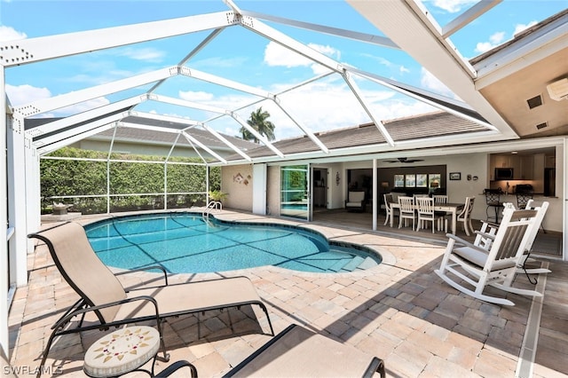 view of swimming pool with a patio, a lanai, and ceiling fan