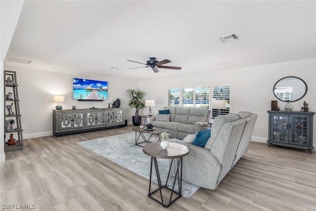 living room with ceiling fan, crown molding, and light wood-type flooring