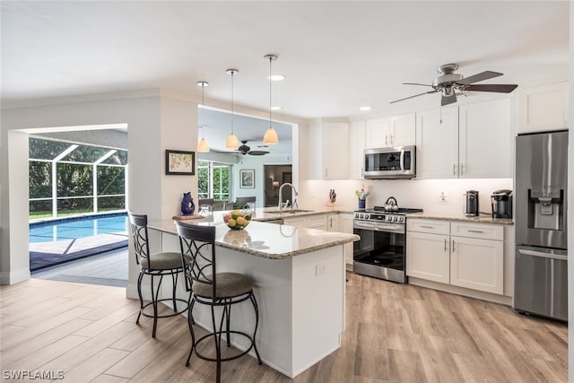 kitchen featuring pendant lighting, light hardwood / wood-style flooring, white cabinetry, and stainless steel appliances