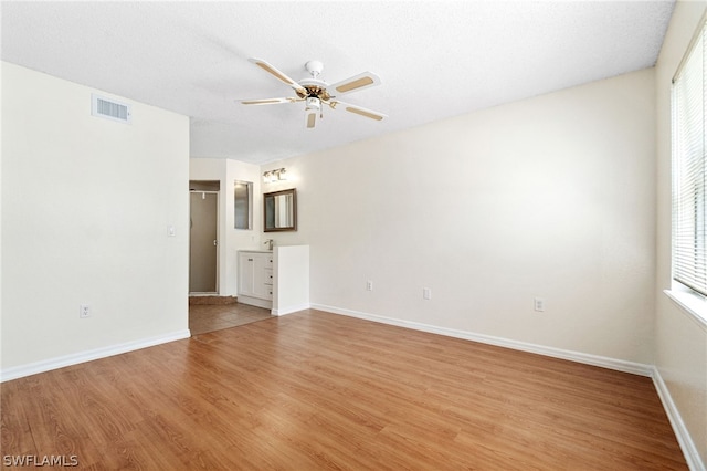 spare room with ceiling fan, light hardwood / wood-style flooring, and a textured ceiling