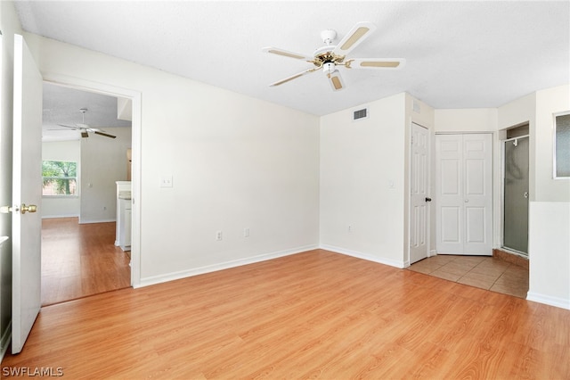 empty room with ceiling fan, light hardwood / wood-style floors, and a textured ceiling