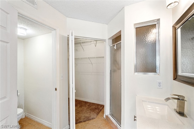 bathroom with tile patterned floors, sink, toilet, a textured ceiling, and a shower with shower door