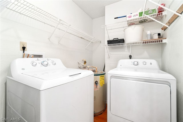 laundry area with wood-type flooring, washing machine and dryer, and water heater