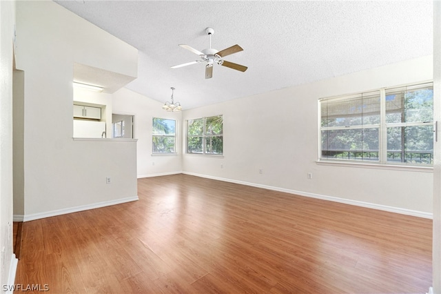 unfurnished room featuring ceiling fan with notable chandelier, wood-type flooring, a textured ceiling, and vaulted ceiling