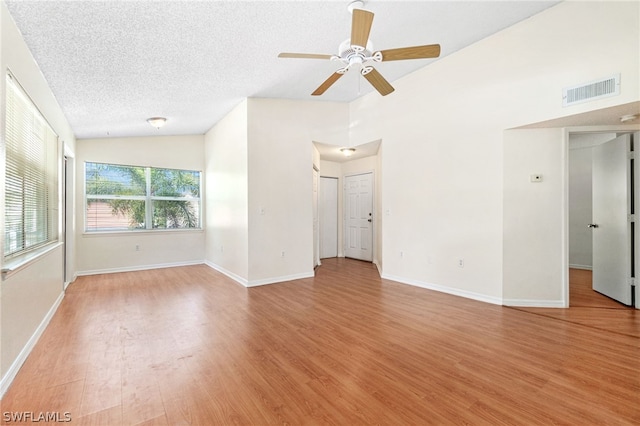 unfurnished room featuring lofted ceiling, ceiling fan, light wood-type flooring, and a textured ceiling