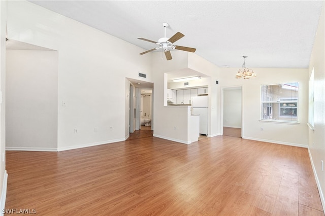 unfurnished living room with hardwood / wood-style floors, ceiling fan with notable chandelier, a textured ceiling, and high vaulted ceiling