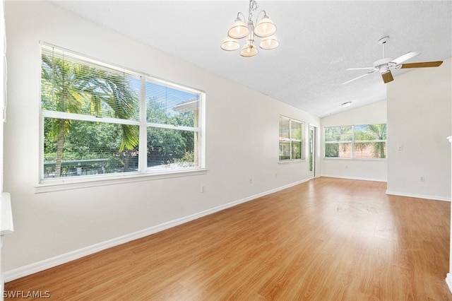 empty room featuring a textured ceiling, light hardwood / wood-style floors, a wealth of natural light, and lofted ceiling