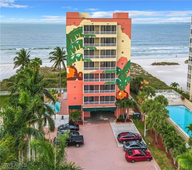 view of building exterior with a beach view, a water view, and a community pool