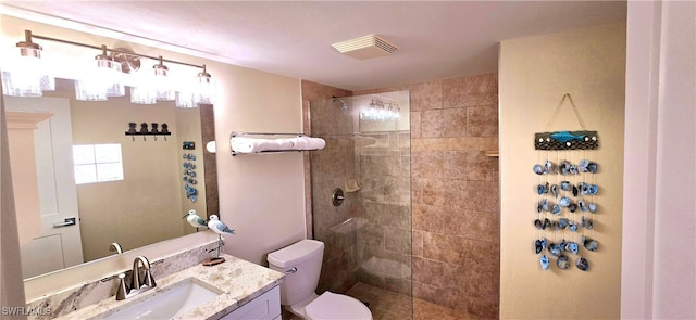 bathroom featuring tiled shower, vanity, and toilet