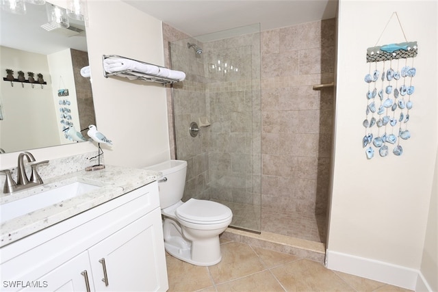 bathroom featuring toilet, a tile shower, vanity, and tile patterned floors