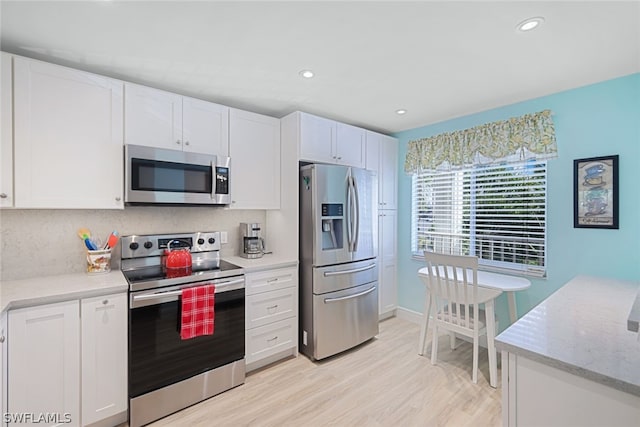 kitchen with appliances with stainless steel finishes, tasteful backsplash, white cabinetry, and light hardwood / wood-style floors