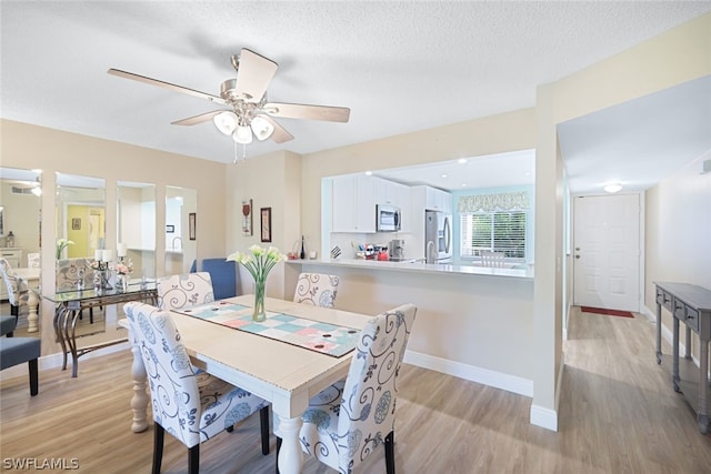 dining area featuring ceiling fan, a textured ceiling, and light wood-type flooring