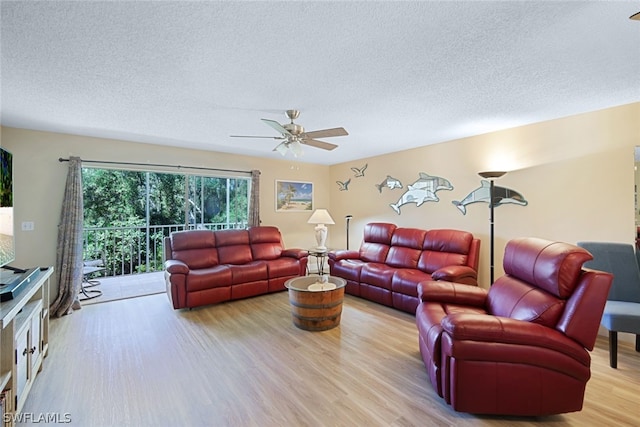 living room featuring ceiling fan, a textured ceiling, and light wood-type flooring