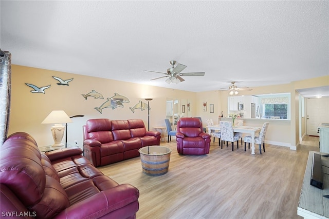 living room featuring a textured ceiling, light wood-type flooring, and ceiling fan