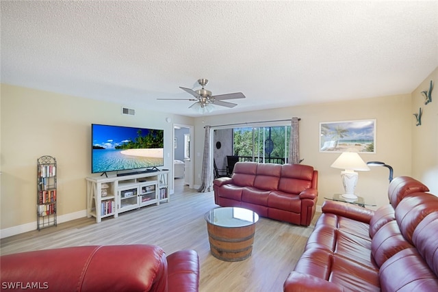 living room with ceiling fan, light hardwood / wood-style flooring, and a textured ceiling