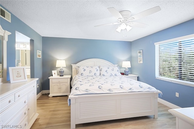 bedroom with ceiling fan, light wood-type flooring, and a textured ceiling