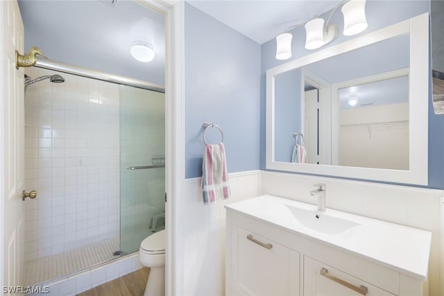 bathroom with hardwood / wood-style floors, vanity, toilet, and walk in shower