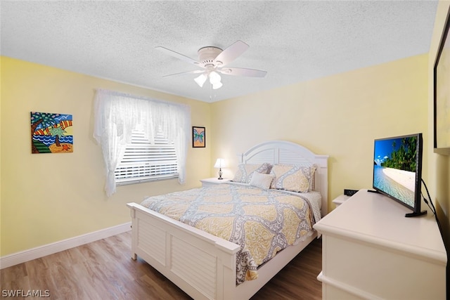 bedroom with hardwood / wood-style flooring, ceiling fan, and a textured ceiling