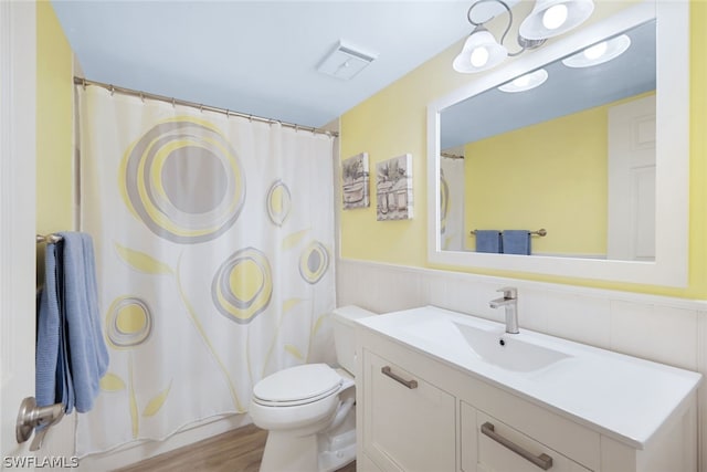 bathroom with hardwood / wood-style floors, vanity, toilet, and curtained shower