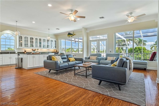 living room with crown molding, hardwood / wood-style floors, french doors, and sink