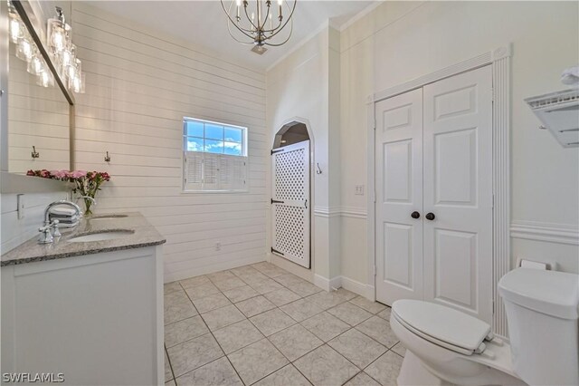 bathroom featuring tile patterned floors, vanity, toilet, and a notable chandelier