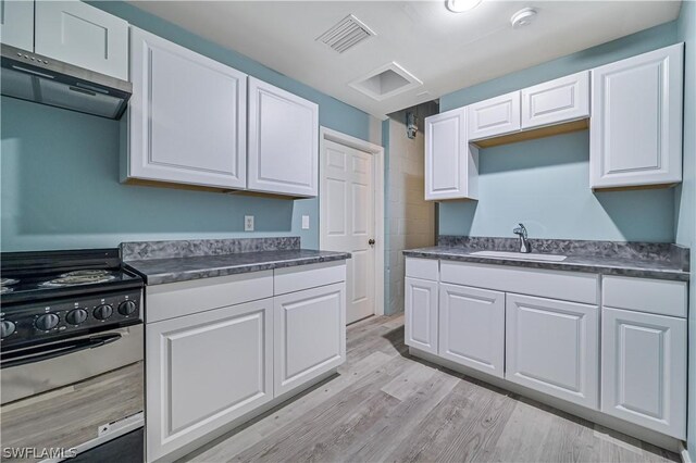 kitchen featuring stainless steel range, light wood-type flooring, white cabinetry, and sink