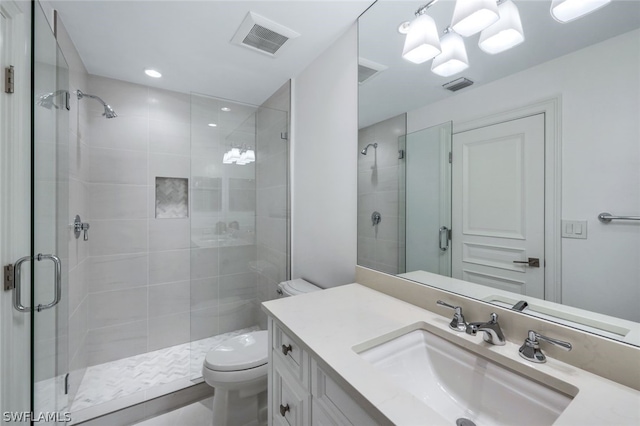 bathroom with a stall shower, visible vents, vanity, and toilet