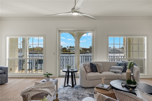 living room with a water view, a ceiling fan, ornamental molding, and wood finished floors