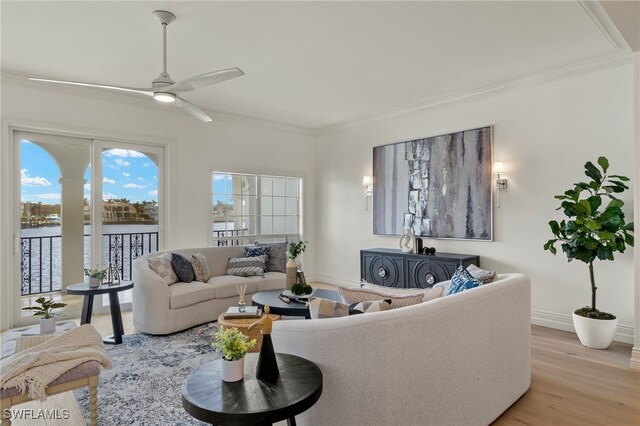 living room with ceiling fan, a water view, crown molding, and light hardwood / wood-style flooring