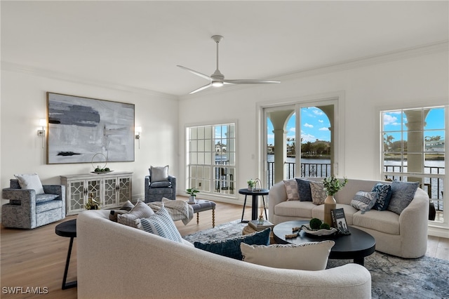 living room with light hardwood / wood-style floors, a water view, ceiling fan, and crown molding