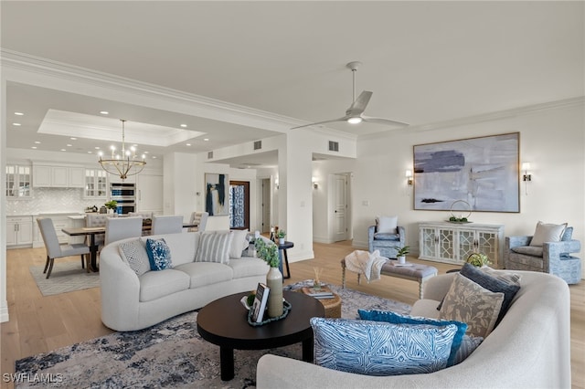 living area featuring light wood-style floors, a raised ceiling, and crown molding