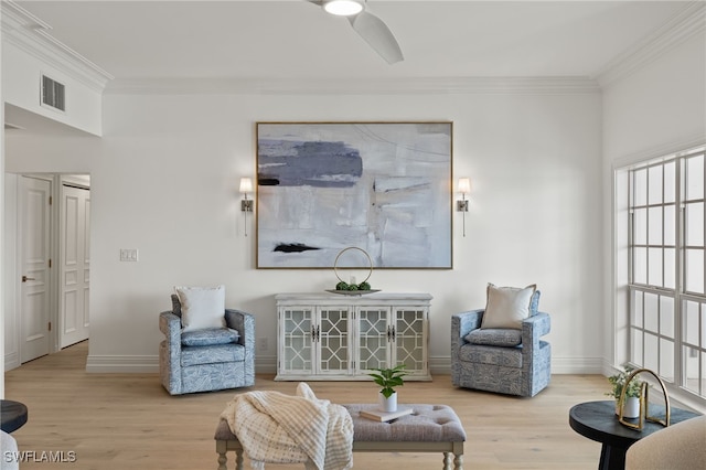 sitting room featuring visible vents, crown molding, baseboards, and wood finished floors