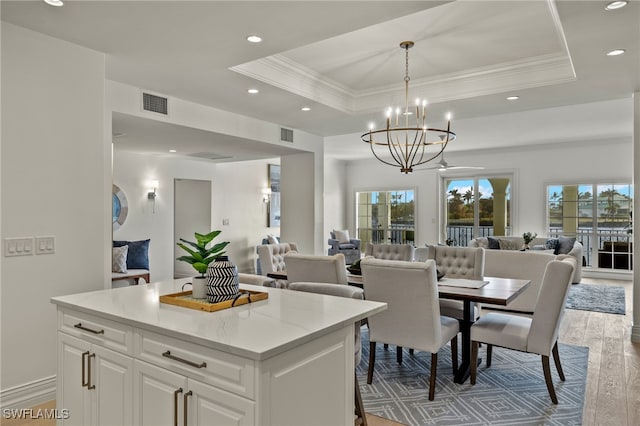 dining area with a tray ceiling, wood finished floors, visible vents, and a healthy amount of sunlight