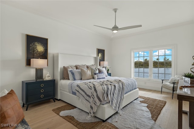 bedroom featuring ornamental molding, light wood-type flooring, and a ceiling fan