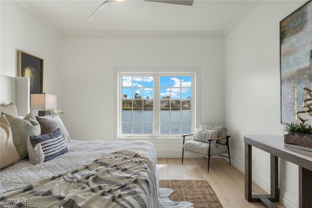 bedroom featuring baseboards, a water view, wood finished floors, and crown molding