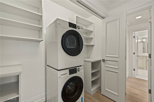 clothes washing area with laundry area, light wood-style flooring, stacked washer and clothes dryer, and crown molding