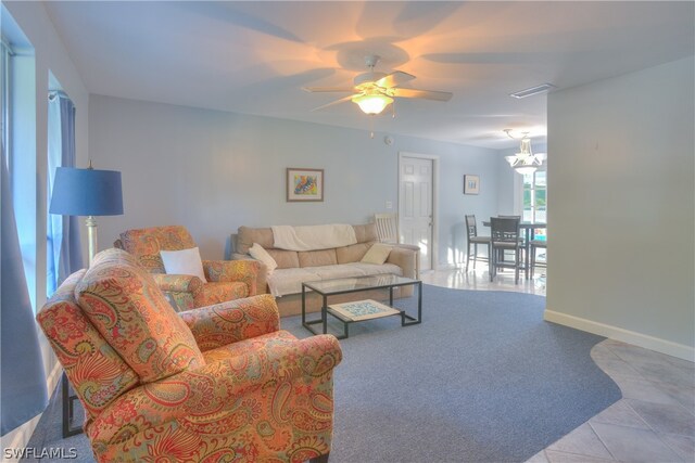 living room featuring ceiling fan with notable chandelier and light tile flooring