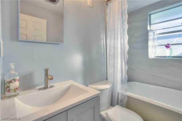 full bathroom with a textured ceiling, toilet, vanity, and shower / tub combo with curtain