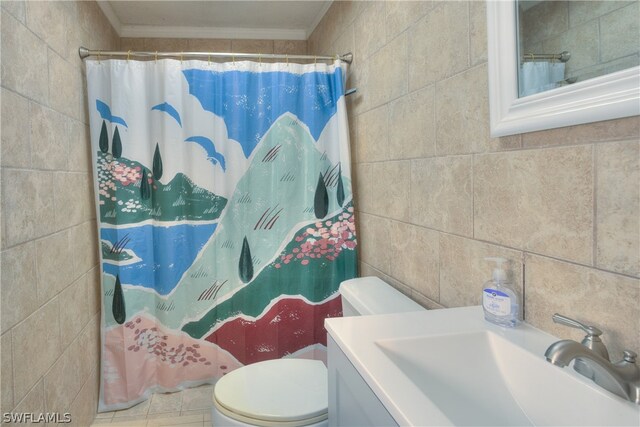 bathroom featuring tile walls, toilet, large vanity, and crown molding