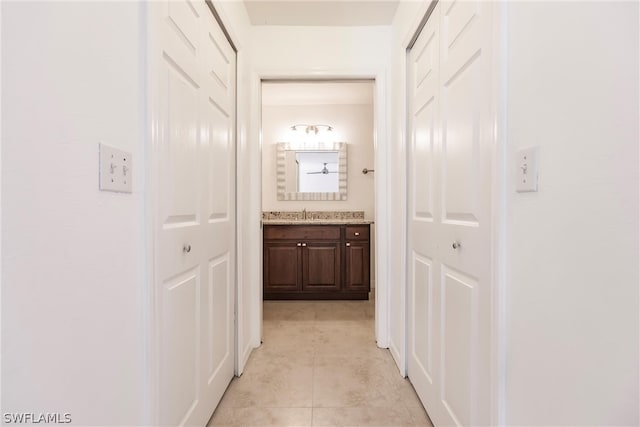 hallway with sink and light tile floors