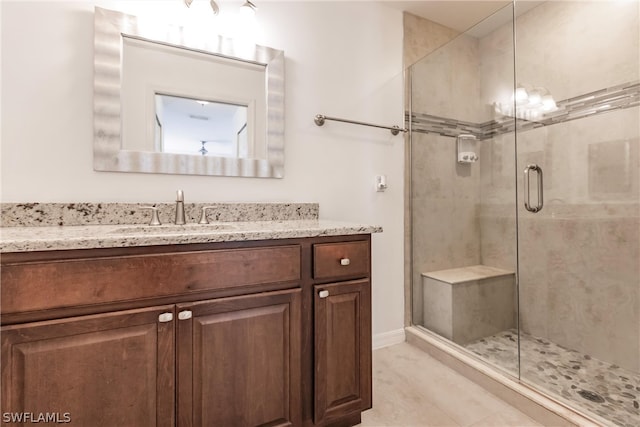 bathroom with an enclosed shower, vanity, and tile flooring