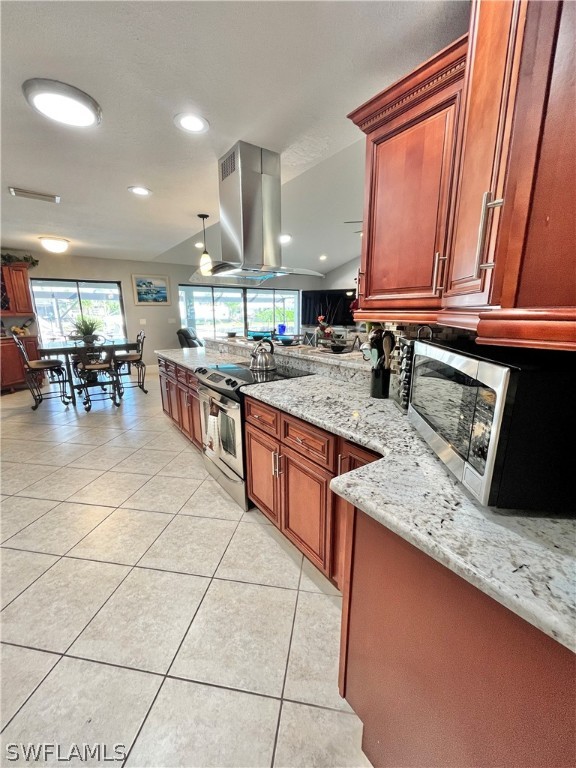 kitchen featuring light stone countertops, stainless steel appliances, island exhaust hood, lofted ceiling, and light tile patterned floors