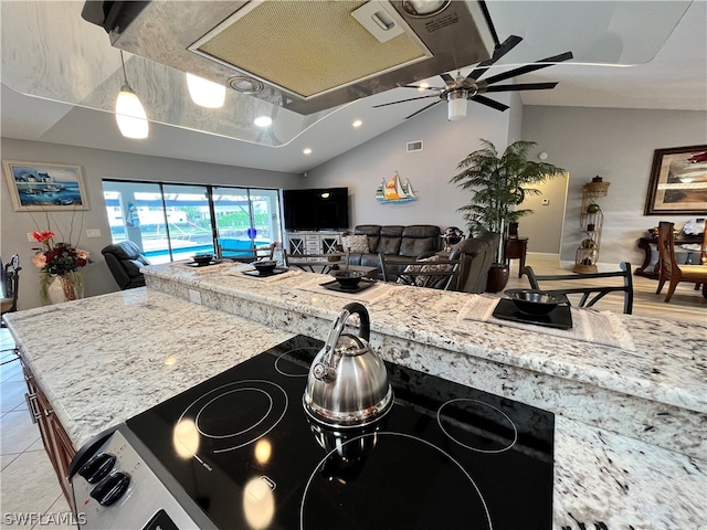 kitchen featuring ceiling fan, a kitchen island, light stone countertops, and lofted ceiling