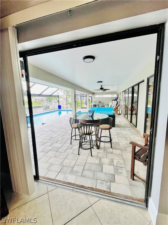 interior space with a lanai, an indoor pool, and ceiling fan