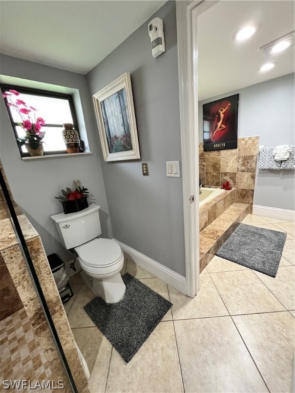 bathroom featuring tile patterned flooring, tiled bath, and toilet