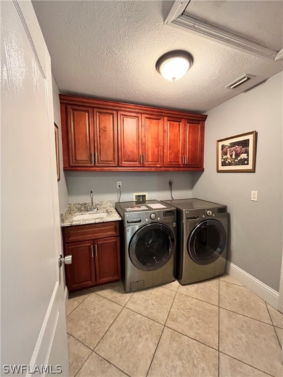 laundry area with sink, light tile patterned floors, cabinets, and a textured ceiling